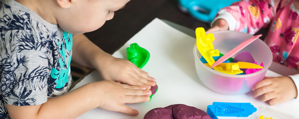 Two children play with play dough while in the Family Counseling Center.