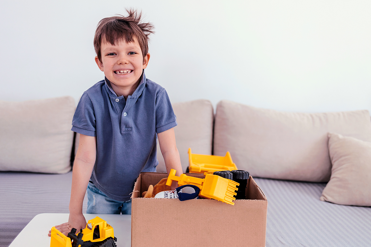 Young boy smiles next to the care package he received from Christmas / Winter Essentials Program at Maine Children's Home