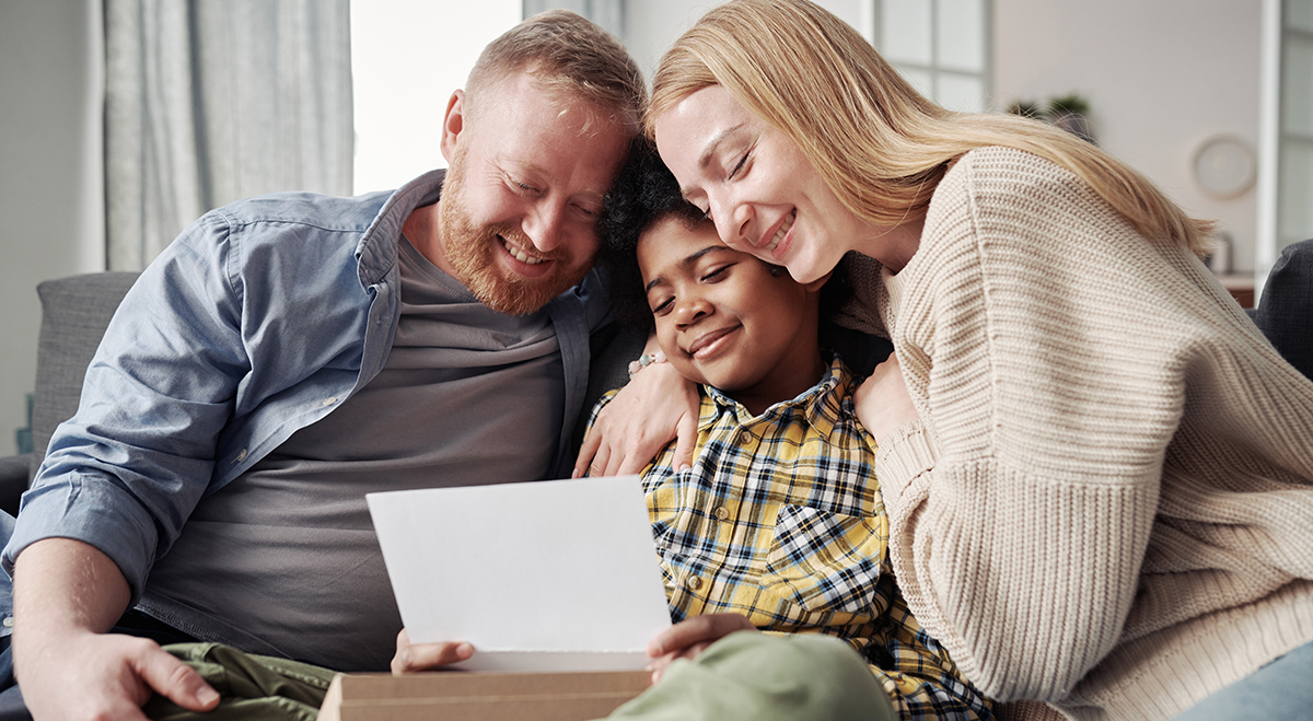 Parents watch son open a gift from his birth parent